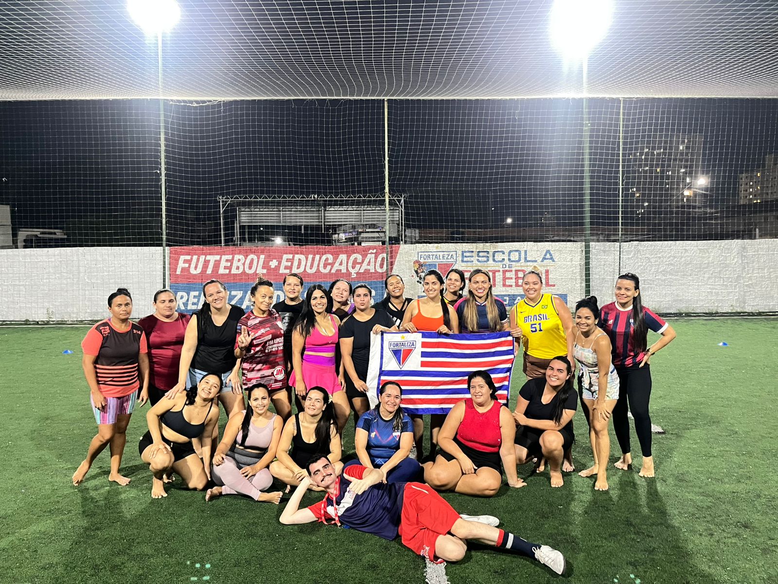 Mães reunidas em campo com a bandeira do Fortaleza